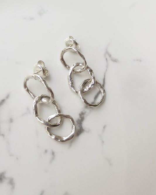 freeform sterling silver chain earrings with 3 rings styled on a marble background