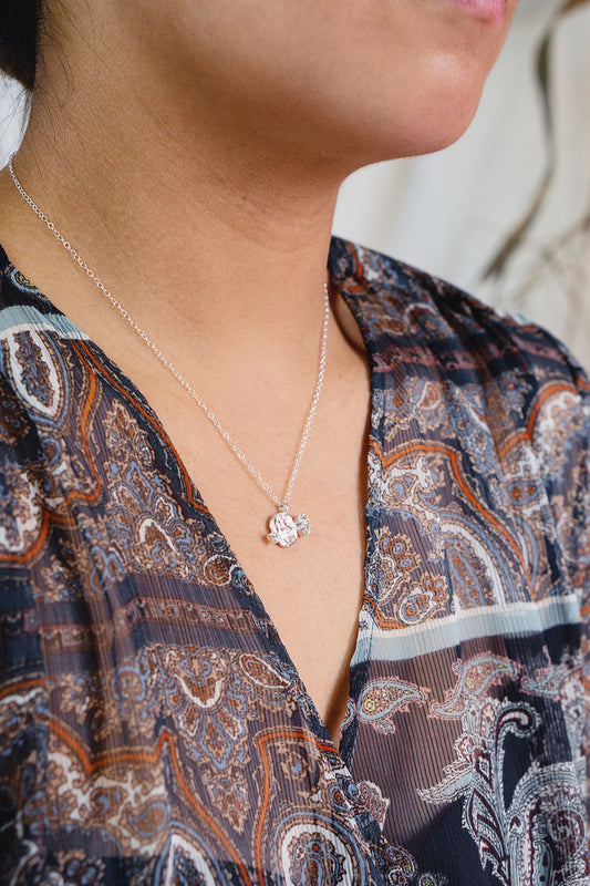 sterling silver textured round pendant necklace with white sapphires styled on model wearing a v-neck patterned dress